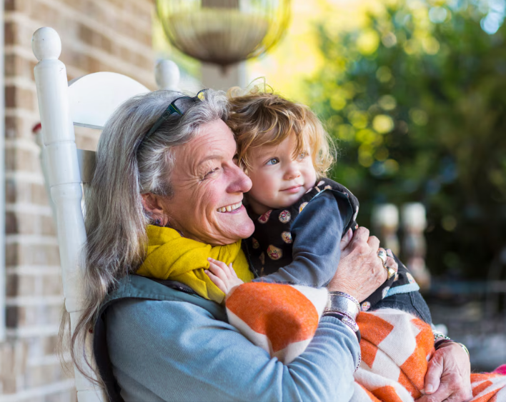 Elderly woman hugging young child outdoors